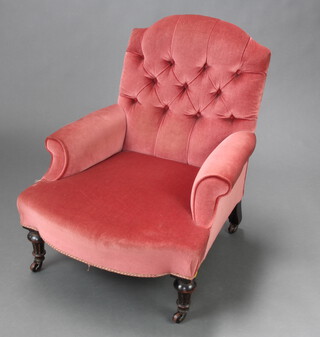 A Victorian armchair upholstered in rose pink buttoned material, raised on turned and fluted ebonised supports with ceramic casters 75cm h x 64cm w x 64cm d (seat 28cm x 39cm) 