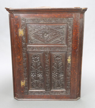 A Victorian carved oak corner cabinet with moulded cornice, fitted shelves enclosed by carved panelled doors 106cm h x 83cm w x 58cm d 