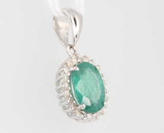 An 18ct white gold oval emerald and diamond pendant, the centre stone approx. 0.88ct, brilliant cut diamonds 0.22ct, 22mm x 11mm, 2 grams 