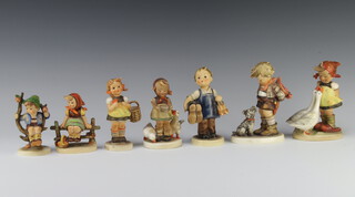 A Hummel figure of a girl sitting on a fence 9cm, ditto girl feeding geese 11cm (chipped), boy holding a bouquet of flowers behind his back with a terrier at his feet 14cm, young boy holding a pair of boots 13cm (stuck), boy sitting in a tree 10cm (stuck), girl carrying a basket 11cm and a girl with 2 geese 13cm (chipped) 