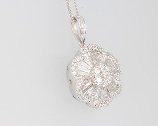An 18ct white gold diamond floral pendant comprising brilliant and tapered baguette cut stones on a silver chain, 15mm wide, 5.2 grams gross, the diamonds approx. 1.59ct 