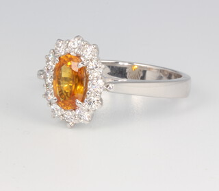 An 18ct white gold orange sapphire cluster ring, the centre stone approx, 1.21ct surrounded by brilliant cut diamonds approx. 0.53ct, size O, 5.5 grams