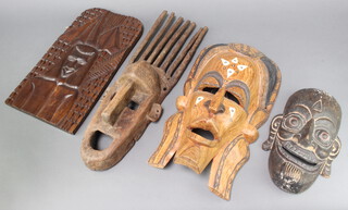 A carved African painted hardwood mask 30cm x 18cm together with 2 other masks and a hardwood panel 43cm x 23cm 

