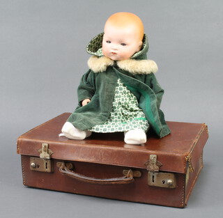 Armand Marseille, a porcelain headed doll with sleep eyes, the head incised A M Germany 3H 3 1/2K, contained in a small leather attache case 12cm x 35cm x 23cm 