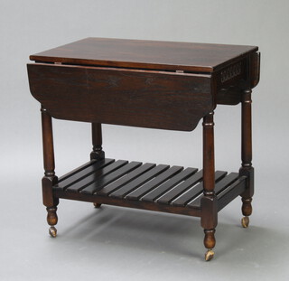 A dark oak 2 tier drop flap tea trolley raised on turned and block supports 67cm h x 68cm w x 42cm d 