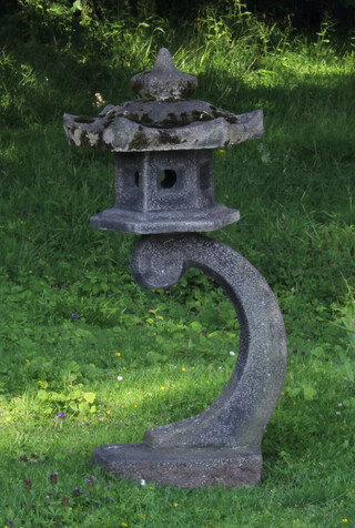 A well weathered hexagonal shaped reconstituted stone Chinese style garden lantern raised on a rectangular base 36cm h x 26cm w