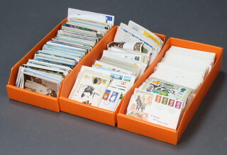 A collection of postcards, PHQ cards and first day covers, contained in 3 shallow orange boxes 

