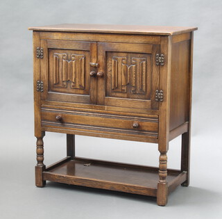 An Ipswich style carved oak cabinet, the upper section enclosed by pair of linen fold panelled doors, the base fitted a drawer, raised on turned and block supports with undertier 86cm h x 78cm w x 40cm (some water damage to the top) 
