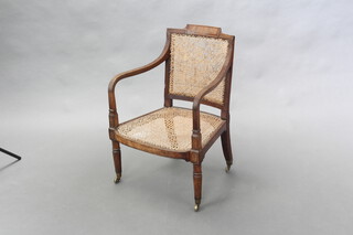 A 19th Century mahogany open arm library chair with cane seat and back raised on reeded supports 76cm h x 53cm w x 52cm d (seat 38cm x 36cm), caning to back of seat damaged in places