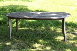 Alexander Rose, an oval well weathered wooden slatted garden table with 2 extra concealed leaves, raised on outswept supports 78cm h x 109cm w x 201cm l when closed x 289cm when extended  