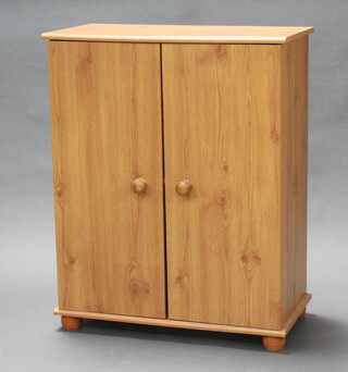 A wooden laminate finished cabinet enclosed by panelled doors with tore handles, raised on bun feet, 87cm h x 70cm w x 35cm d 