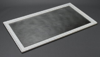 A rectangular bevelled plate wall mirror contained in a white and silver decorative frame 135cm x 77cm (silvering to the mirror is showing signs of deterioration)  