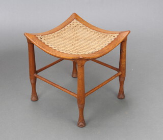 A late 19th Century walnut 'Thebes' stool with dish shaped woven seat raised on turned supports, Likely to be Liberty & Co