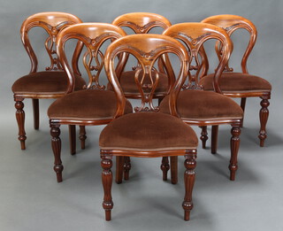 A set of 6 Victorian style tulip back dining chairs with pierced vase shaped slat backs and over stuffed seats, raised on turned and reeded supports 