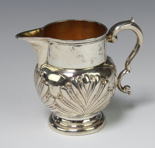An embossed silver cream jug, marks rubbed, 154 grams 