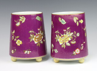 A pair of Edwardian circular tapered purple ground vases decorated with flowers raised on ball feet 16cm