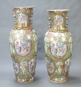 A near pair of massive mid 20th Century oviform famille rose vases with twin lion handles, decorated with panels of figures on pavilion terraces on a ground of flowers, fruits and insects 146cm h and 139cm h 