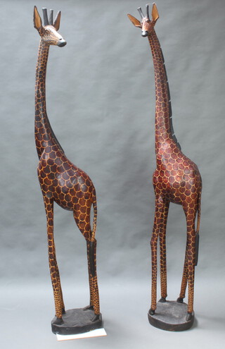 A large and impressive pair of African carved hardwood figures of giraffes raised on circular bases 216cm h x 31cm w and 214cm h x 31cm 