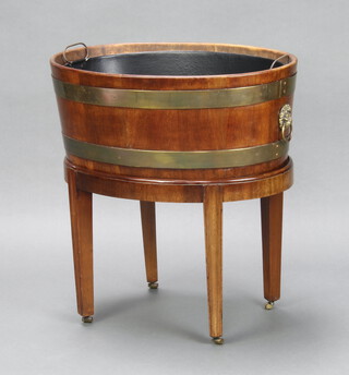 A Georgian oval coopered mahogany cellarette wine cooler with zinc liner and lion mask handles, raised on a detachable base raised on square tapered supports and brass casters 62cm h x 60cm w x 45cm d 