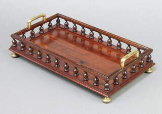 A rectangular brass and mahogany twin handled book tray with amboyna turned decoration raised on brass bun feet 7cm x 36cm x 21cm 