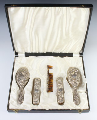 A Sterling silver repousse dressing table set comprising 2 clothes brushes, 2 hair brushes and a comb, decorated with masks and scrolls with an engraved monogram, boxed 