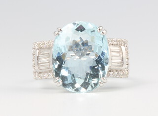 An 18ct white gold oval aquamarine and diamond ring, the centre stone approx 6.53ct, the brilliant and baguette cut diamonds approx. 0.36ct, 6.8 grams, size M 1/2