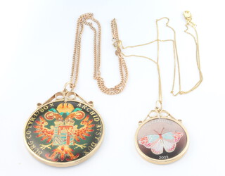 Two enamelled silver coins set in 9ct mounts with 9ct yellow gold chains, chains 5.2 grams 