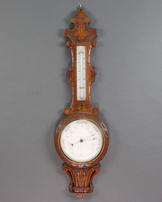 A Victorian aneroid barometer and thermometer contained in a carved oak wheel case  88cm x 26cm 
