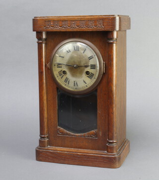 An Edwardian Art Nouveau 8 day striking mantel clock with silvered dial and Roman numerals contained in an oak case with pillars to the side 34cm h x 21cm w x 13cm d 