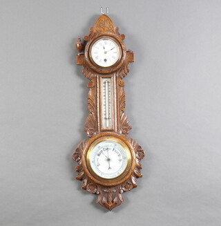 A Victorian wheel aneroid barometer and thermometer with porcelain dial contained in a carved oak case, the top surmounted by a timepiece with 8cm enamelled dial 67cm h x 24cm w 