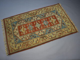 An orange, blue and white Caucasian style rug the central medallion with 5 stylised diamonds to the centre 201cm x 124cm 