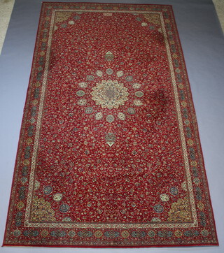 A red and green ground machine made Persian style carpet with central medallion 409cm x 229cm 