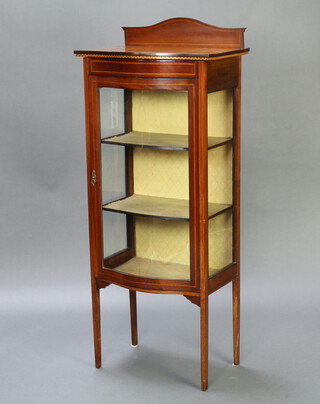 An Edwardian inlaid mahogany bow front display cabinet with arched raised back, fitted shelves enclosed by a glazed panelled door, raised on square tapered supports 142cm h x 58cm w x 40cm d 