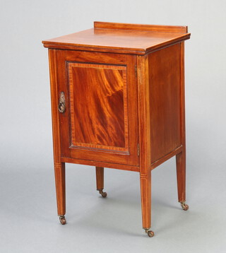 An Edwardian inlaid and crossbanded mahogany bedside cabinet with raised back, enclosed by a panelled door, raised on square tapered supports with casters 70cm h x 41cm w x 37cm d  