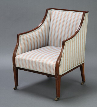 An Edwardian mahogany show frame armchair upholstered in striped material, raised on square tapered supports, brass caps and casters 82cm h x 60cm w x 56cm d (seat 36cm x 38cm) 
