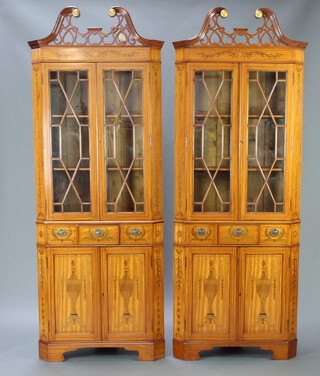 A handsome pair of 20th Century Hepplewhite style painted satinwood corner cabinets with pierced and broken pediments, decorated throughout with lidded urns, the upper sections fitted shelves enclosed by astragal glazed panelled doors above 1 long and 2 dummy drawers, above cupboards enclosed by panelled doors, raised on bracket feet 217cm h x 80cm w x 53cm d 