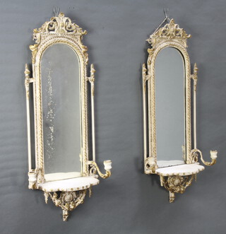 A pair of 19th Century arched plate mirrors contained in a gilt and white painted plaster frames, the base with shelf flanked by a pair of sconces 92cm h x 32cm  
