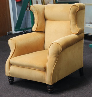 A winged armchair raised on turned supports upholstered in yellow material 85cm h x 76cm w x 78cm d (seat 36cm x 44cm) 