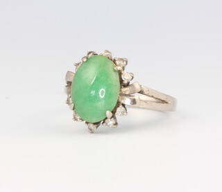A white metal ring set with an oval jadeite stone 4.7 grams, size O 1/2, stamped 18k  