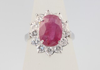 An 18ct white gold oval ruby and diamond cluster ring, the centre stone 3.17ct, the brilliant cut diamonds 1.65ct, size N, 6.1 grams
