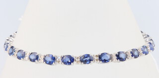 An 18ct white gold oval sapphire and diamond line bracelet, the sapphires 10.73ct, the diamonds 0.55ct, 18cm, 8.4 grams
