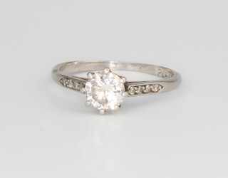 A platinum single stone diamond ring with 4 diamond chips to each shoulder, the centre stone 0.75ct