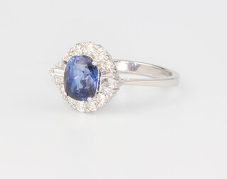 An 18ct white gold oval sapphire and diamond cluster ring, centre stone 1.73ct, surrounded by tapered baguette diamonds 0.15ct and brilliant cut diamonds 0.42ct, size N, 3.6 grams