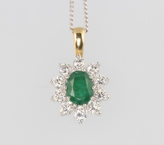 An 18ct oval white gold emerald and diamond cluster pendant, the centre emerald 1ct, the brilliant cut diamonds 1.25ct, 22mm x 12mm, on a silver chain 44cm 4.4 grams
