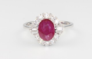 An 18ct white gold oval ruby and diamond ring, the centre stone 1.26ct surrounded by brilliant and baguette cut diamonds 0.5ct, size M 1/2, 3.5 grams 