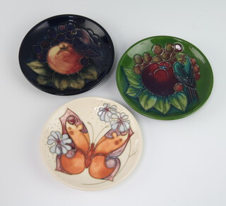 Moorcroft, a contemporary green ground dish decorated with bird on fruit design, circa 1992, 11.5cm, a ditto blue ground dish 11.5cm and a cream ground dish decorated the butterfly and forget me not pattern, designed by Rachel Bishop, circa 1993, 11.5cm
