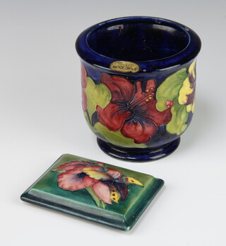 A Walter Moorcroft blue ground jardiniere decorated with hibiscus, signed monogram and impressed marks 13cm, together with a Moorcroft rectangular box lid decorated the orchid design 12cm x 9cm 

