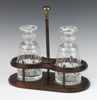 A pair of mallet shaped decanters with mushroom stoppers in a mahogany finished 2 bottle rack 