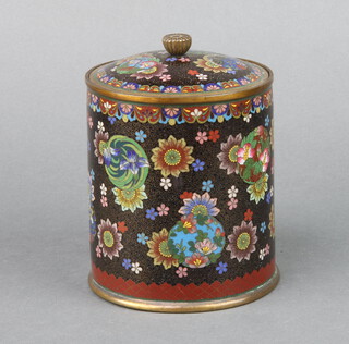 A black and floral ground cloisonne enamel cylindrical jar and cover decorated butterflies and flower heads 12cm h x 11cm diam. 

