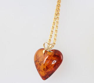 A Continental yellow metal necklace 48cm with an amberoid heart pendant, 10 grams